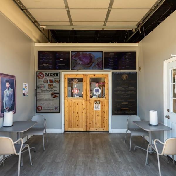 Small restaurant interior with two tables, menu boards, and wooden double doors.
